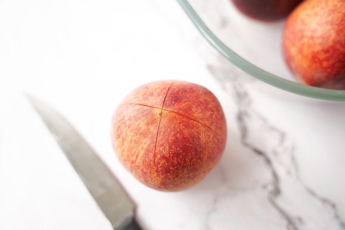 X on a peach with knife on counter