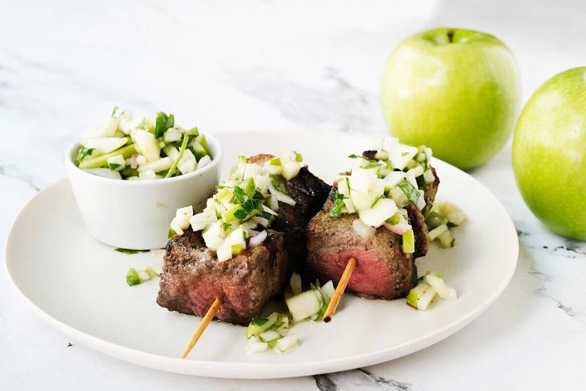 Steak skewers served with apple chimichurri on top