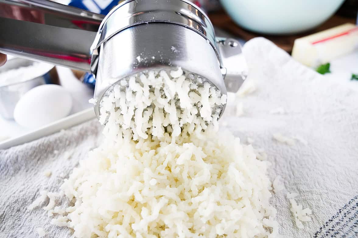potato ricer ricing boiled potato on towel to remove excess water