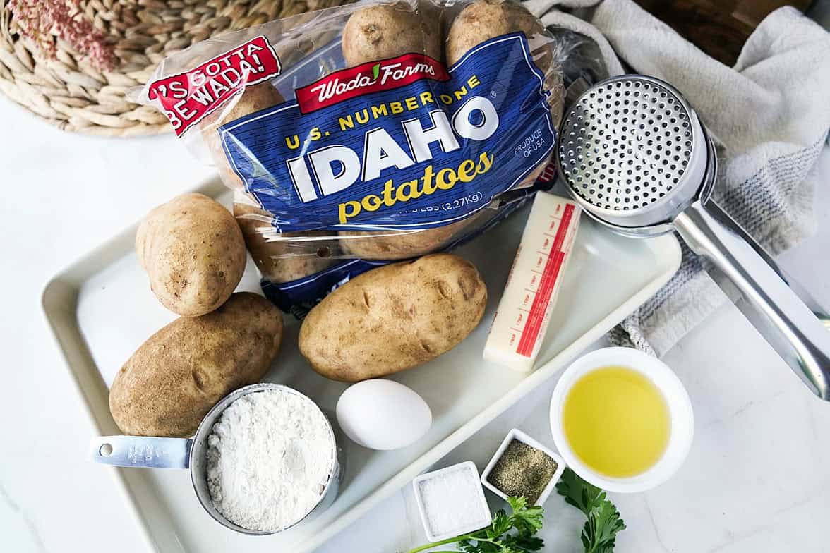 overhead shot of ingredients to make potato gnocchi recipe: wada farms Idaho potatoes, flour, egg, salt, butter, pepper, olive oil and a potato ricer