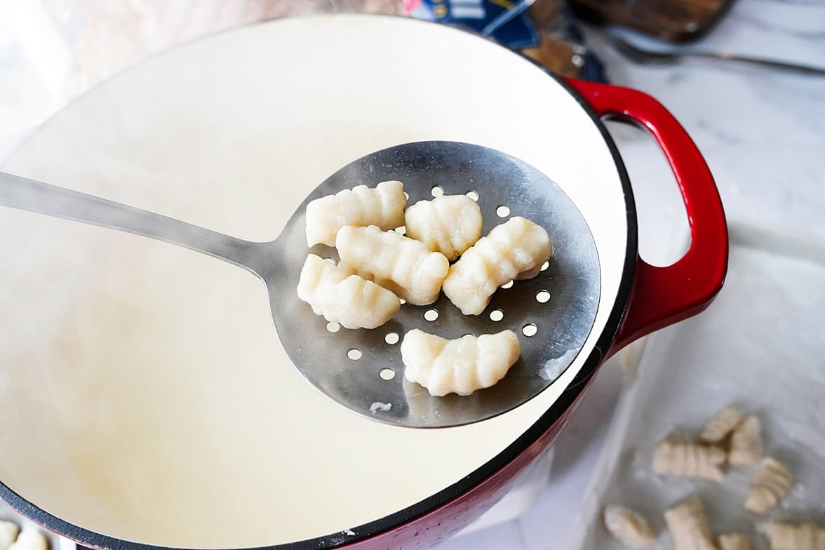 slotted spoon with 6 pieces of potato gnocchi after being boiled