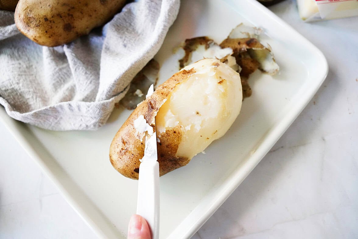knife slicing potato skin off after being boiled