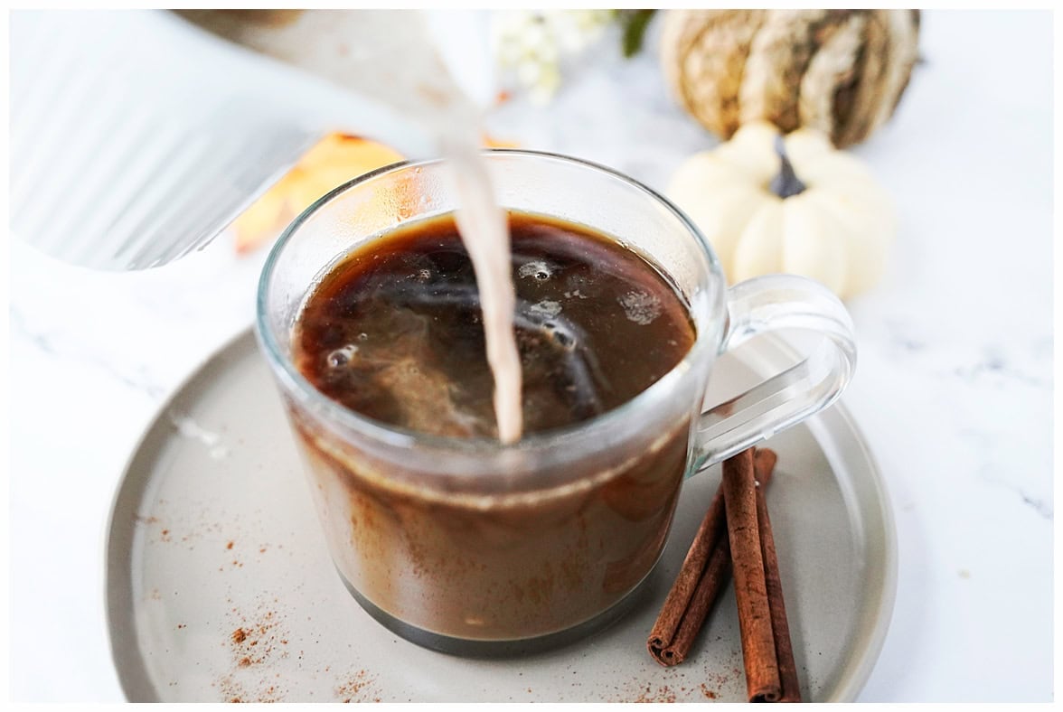 glass coffee mug with coffee and homemade pumpkin spice coffee creamer being poured in
