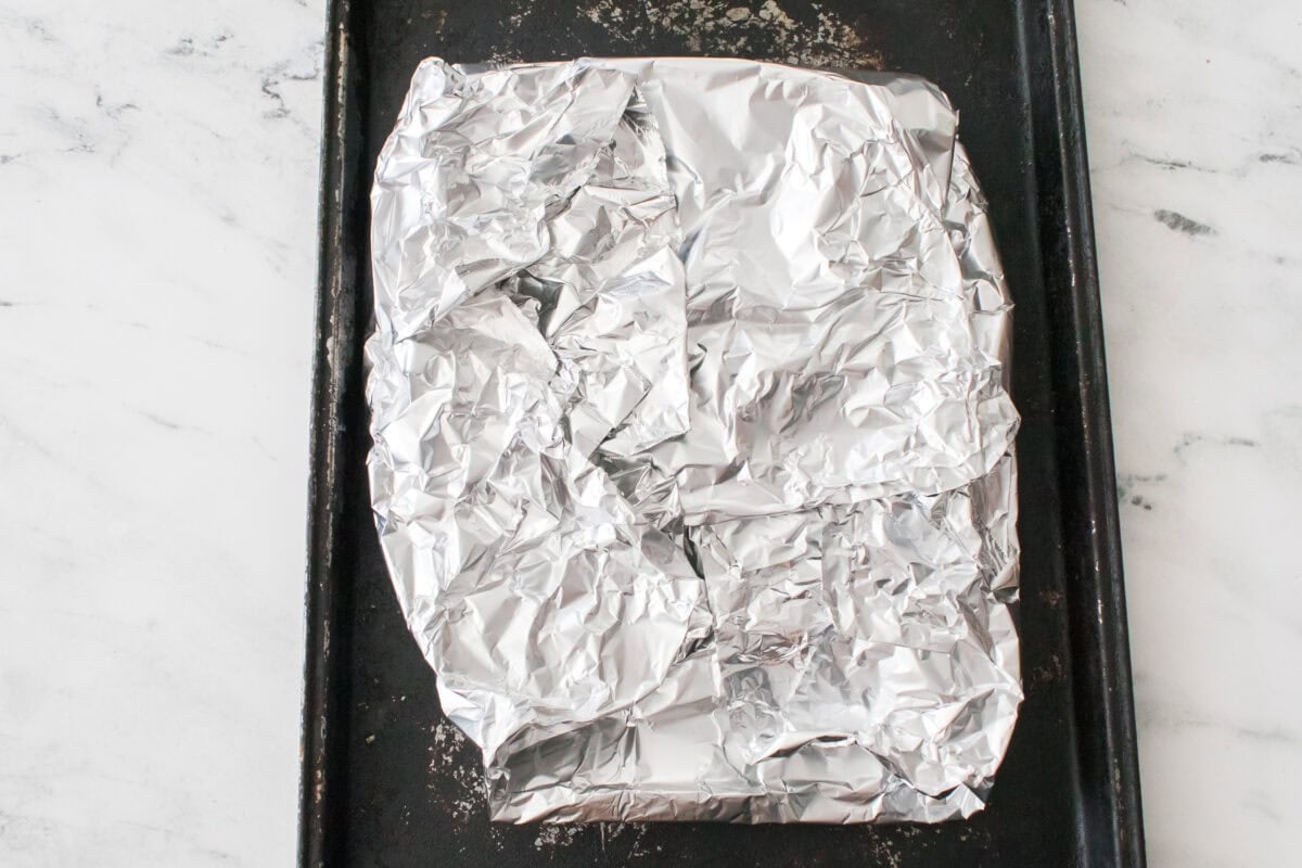 baking sheet with aluminum foils with potatoes inside