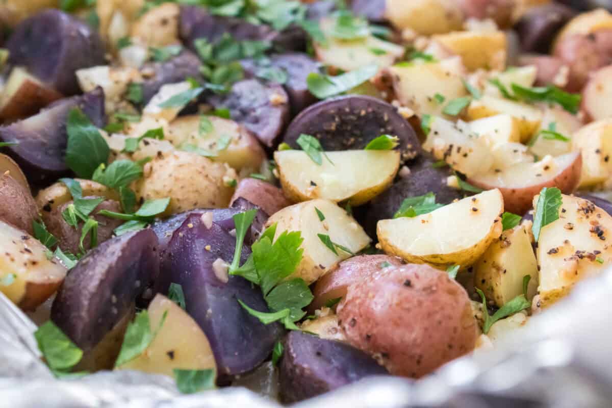 close up hortizontal shot of quartered smalls medley potatoes, after baking with garlic, onions, salt and pepper and garnished with parsley