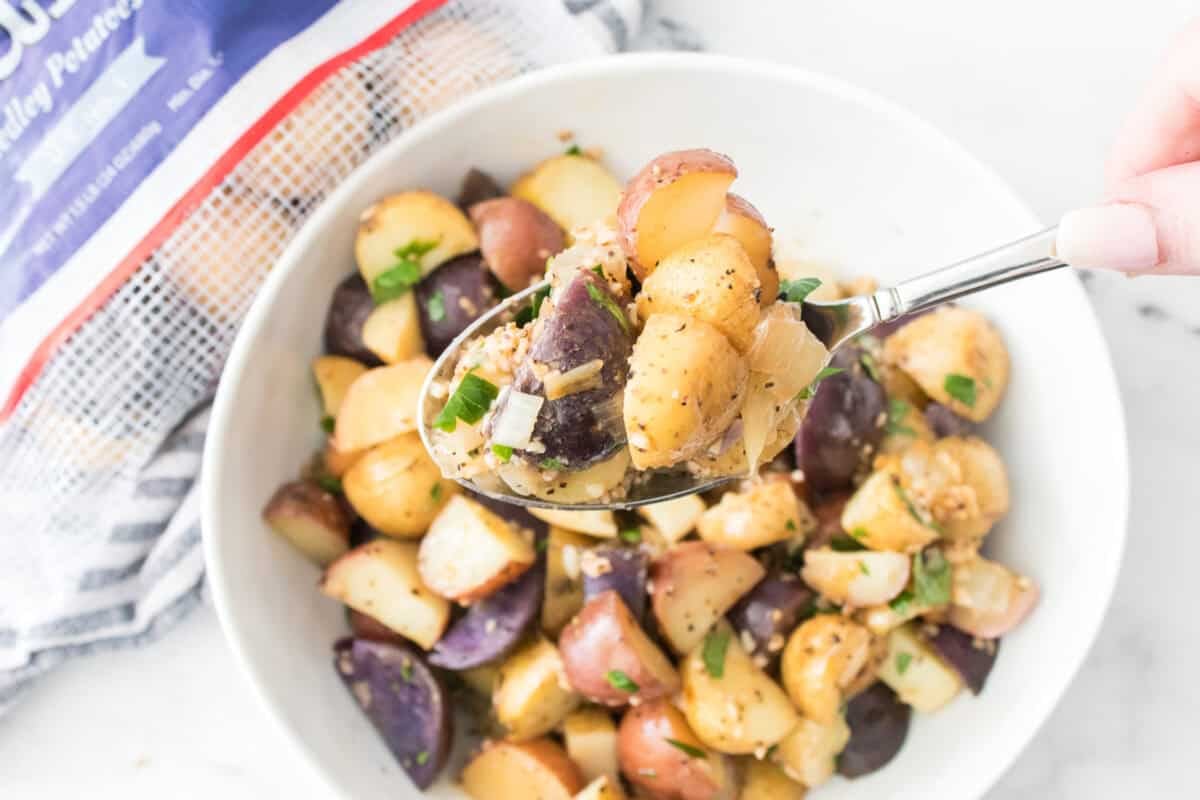 spoon holding foiled potatoes over serving bowl full