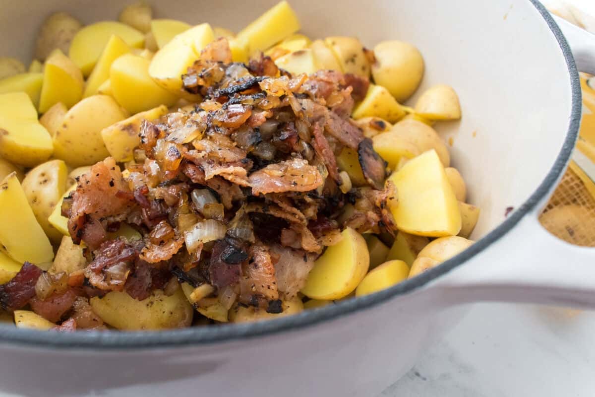 close up shot of bacon and onion mixture over top of boiled small potatoes that have been quartered