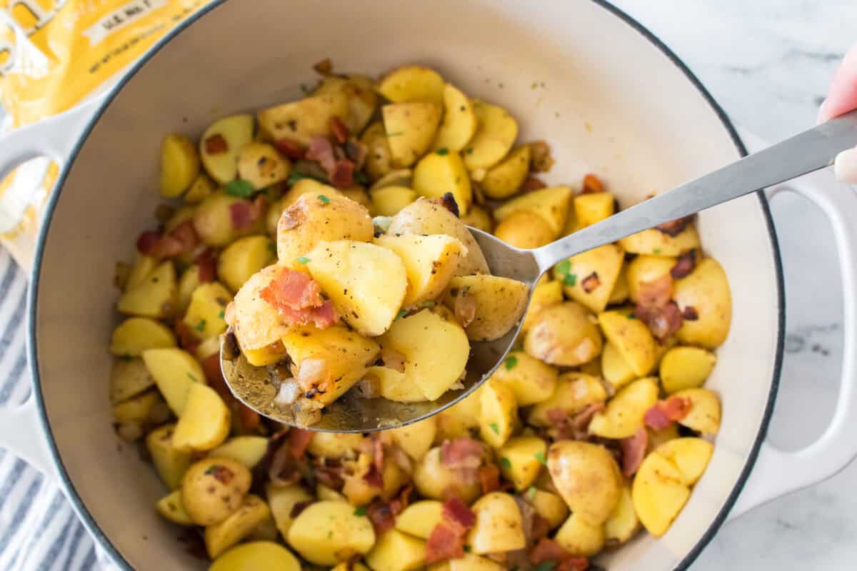 overhead shot of spoonful of german potato salad over white dutch oven