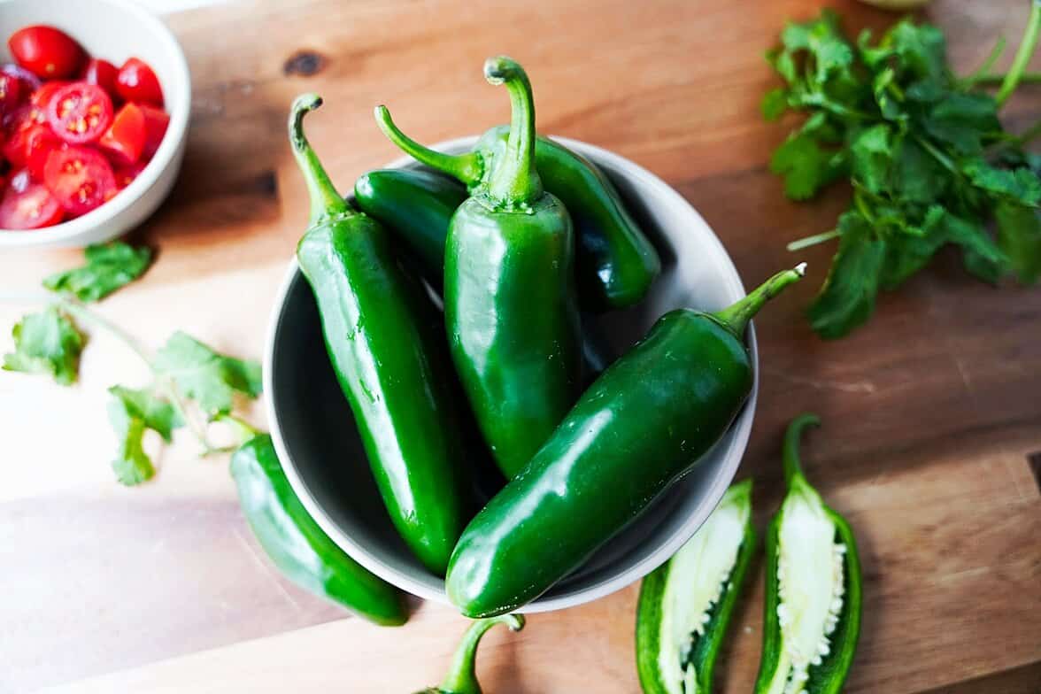 jalapeno peppers in a bowl on a cutting board
