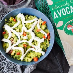 overhead shot of spiderweb guacamole with bag of Westfalia Fruit avocados with a