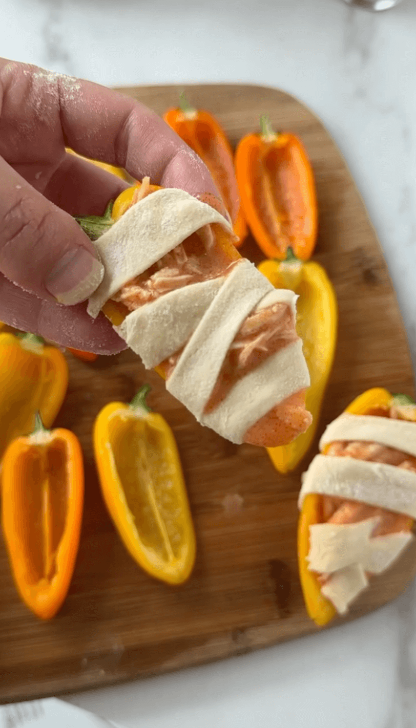 Wrapping the mini bell pepper with the dough to look like mummies
