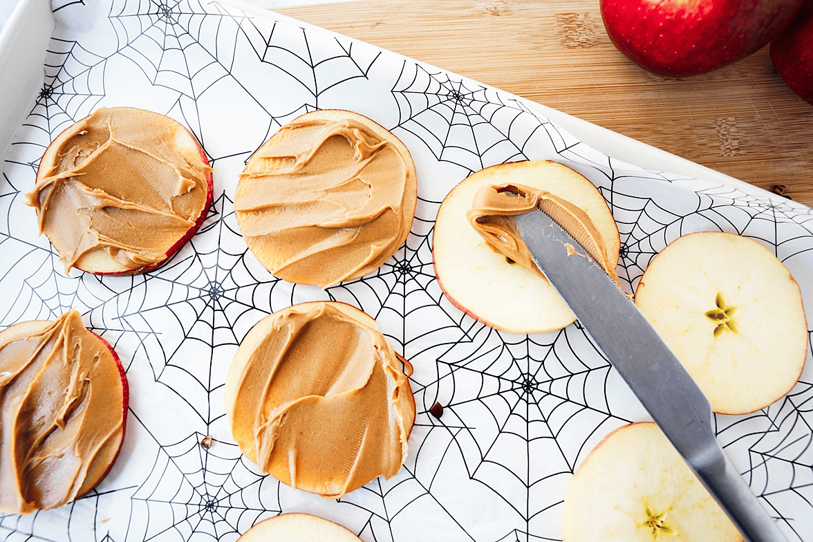 Spread peanut butter onto apple rounds with a butter knife