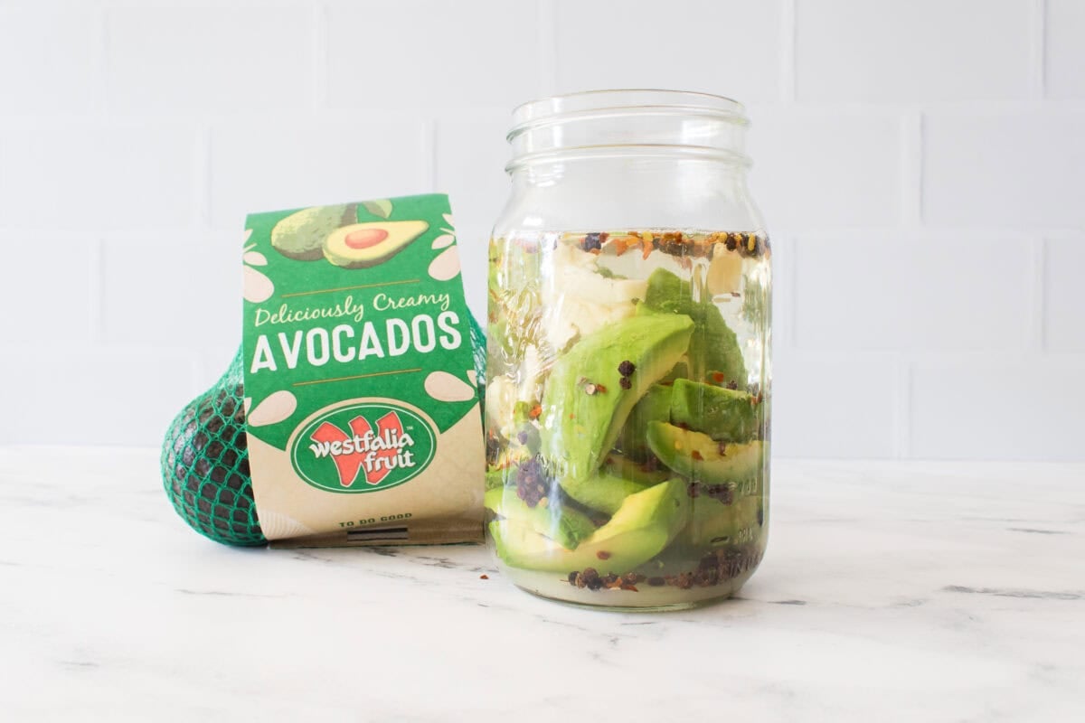 bag of westfalia fruit avocados with big mouth mason jar with avocados, peppercorns, red pepper flakes and sugar, water and vinegar