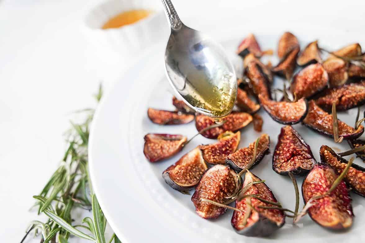 Honey being poured on a plate full of oven roasted figs