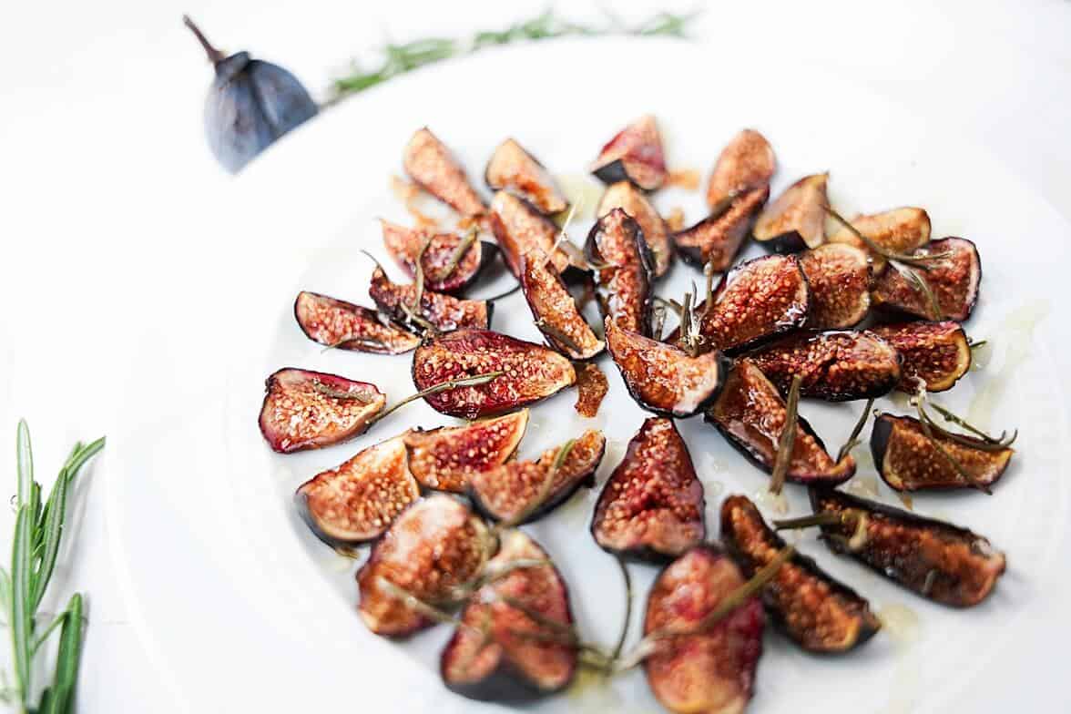 Side view of oven roasted figs on a white plate