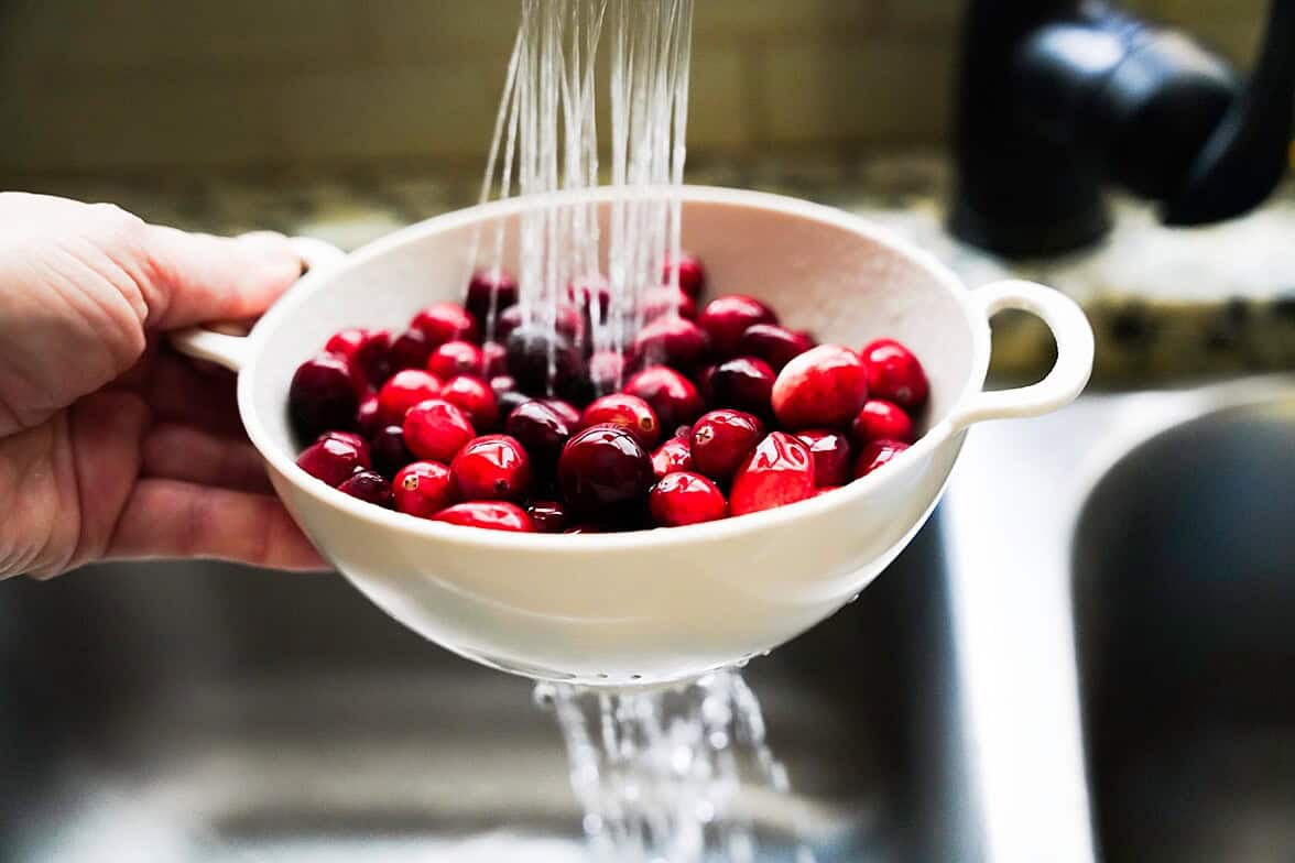 Water rinsing cranberries in a white collander