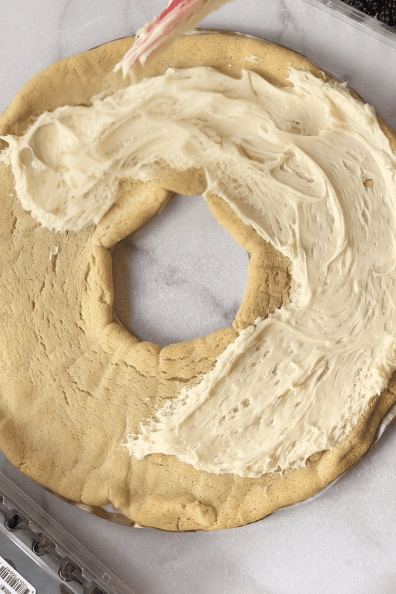 Spreading icing on baked cookie wreath