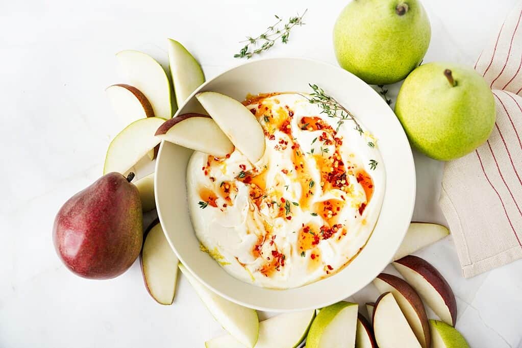 overhead view of finished Hot Honey Whipped Ricotta Dip with pear slices and whole pears surrounding bowl