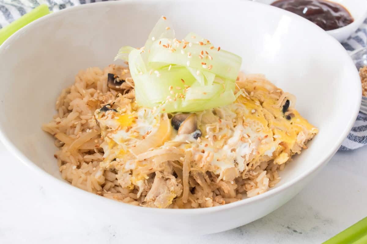 close up 45 degree shot of Japanese Oyakodon: Chicken and Mushroom Bowl topped with shaved celery and toasted sesame seeds
