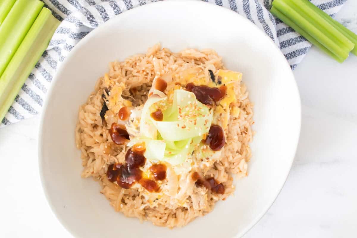 overhead shot of Japanese Oyakodon: Chicken and Mushroom Bowl in white serving bowl with sliced celery on both sides