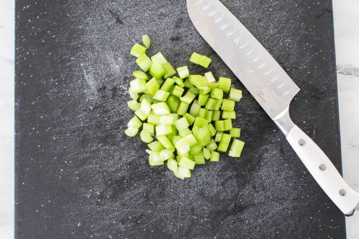 chopped celery on cutting board with knife