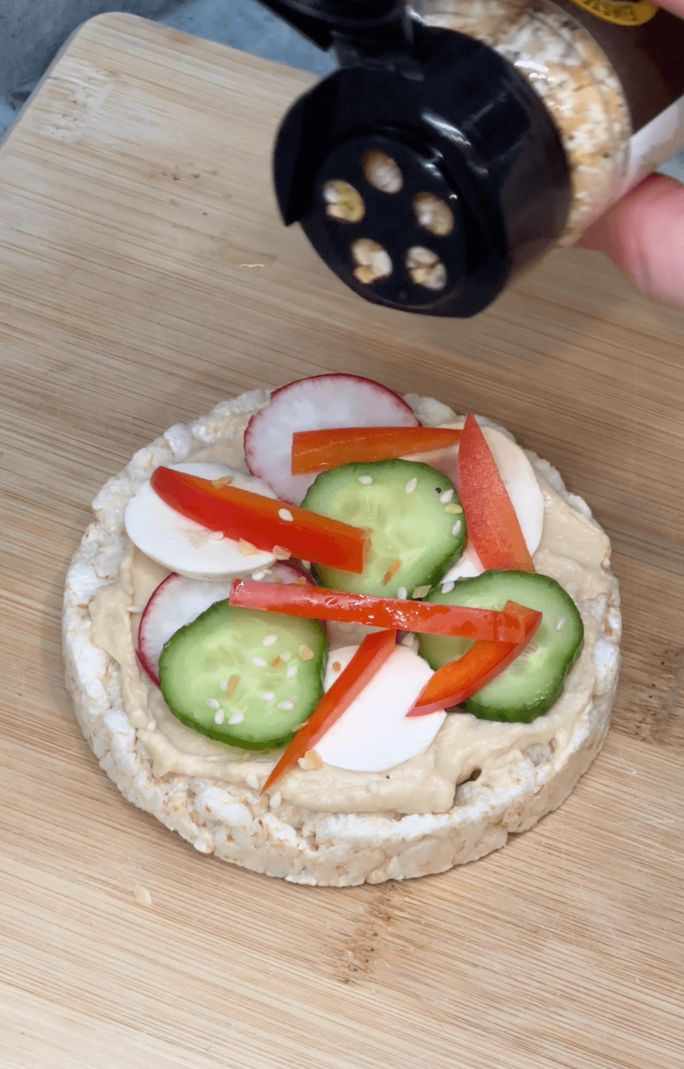 Everything Bagel Seasoning getting sprinkled onto Veggie Rice Cake Pizza