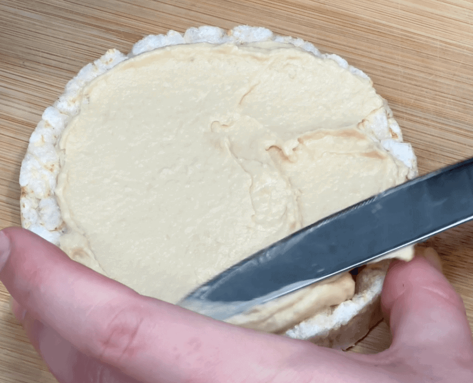 Spreadding hummus on rice cake