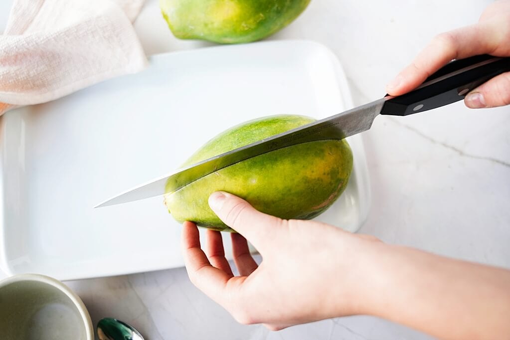 Knife going down the center of a papaya