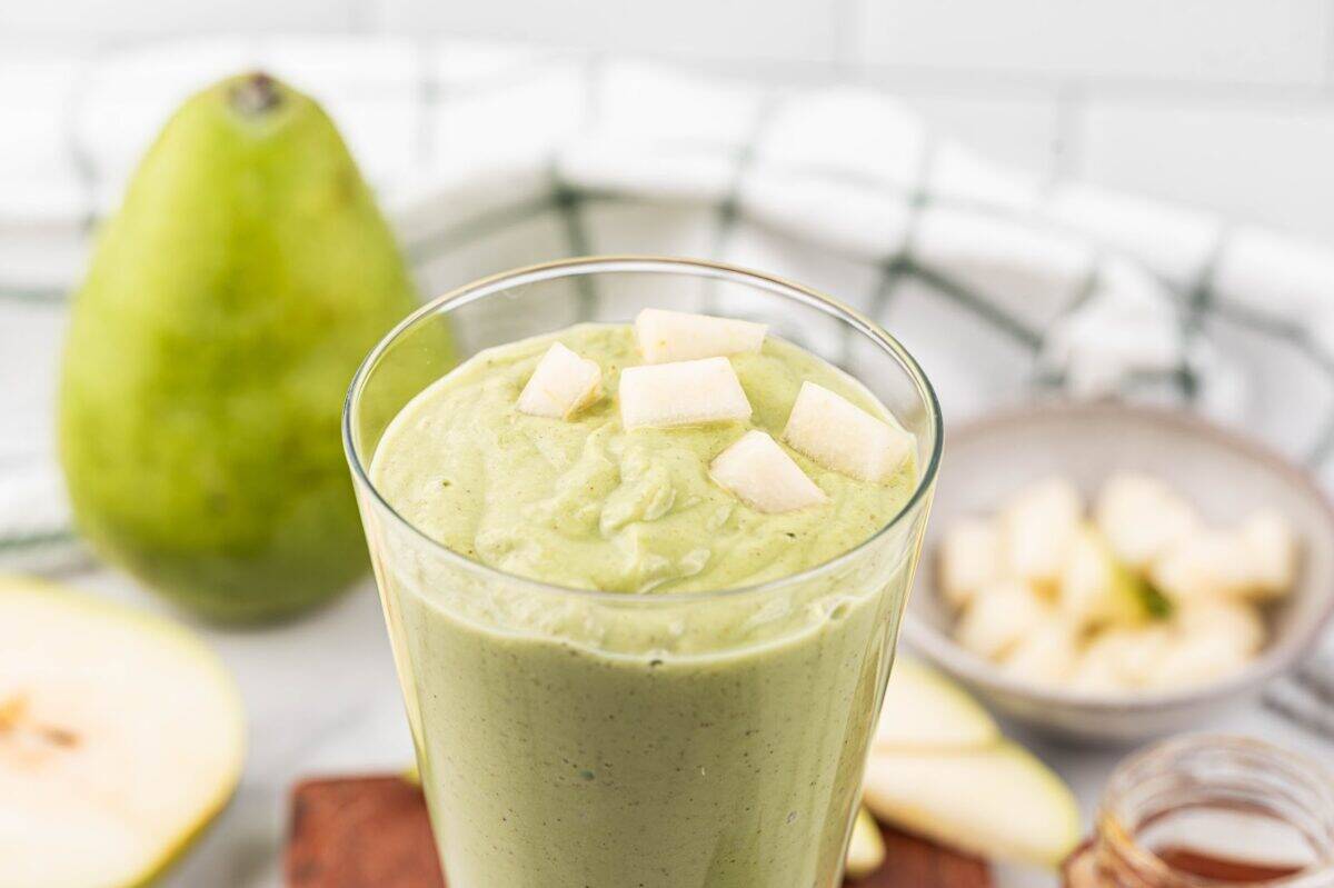 Fresh diced pears on top of a blended green smoothie