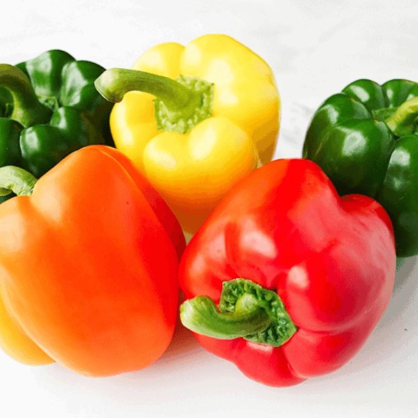 beauty shot of 5 bell peppers: 2 green, 1 yellow, 1 orange and 1 red