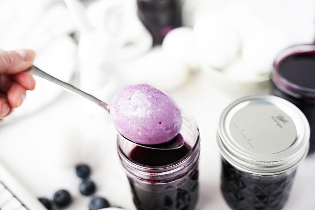Spoon scooping out egg in the blueberry dye mason jar