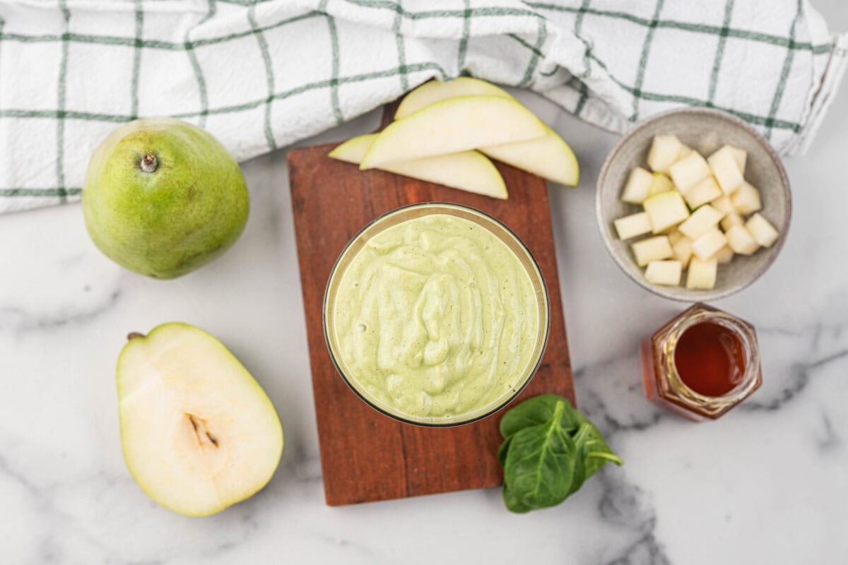 overhead view of green goddess smoothie with whole pear, half pear, slices of pear and cubed pears in the picture