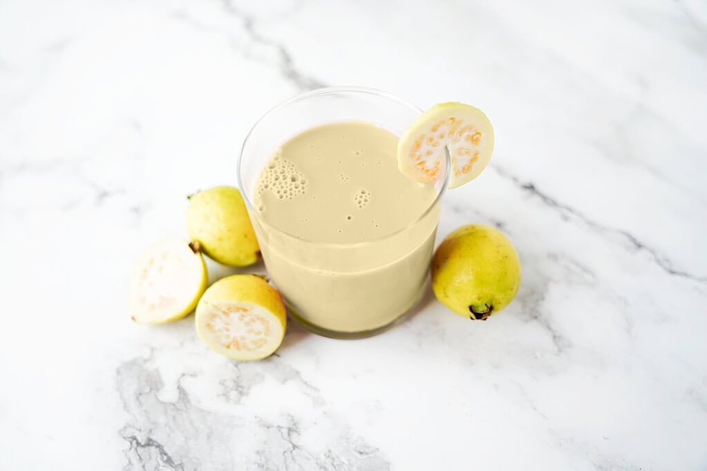 Guava juice in a glass with guavas surrounding