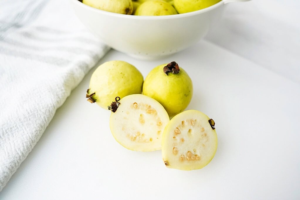 Guava cut in half with whole guavas behind them