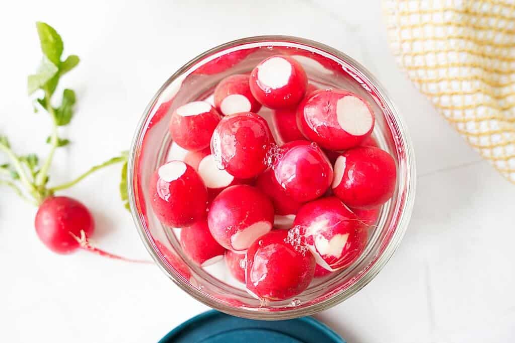 Overhead view of whole radishes submerged in water