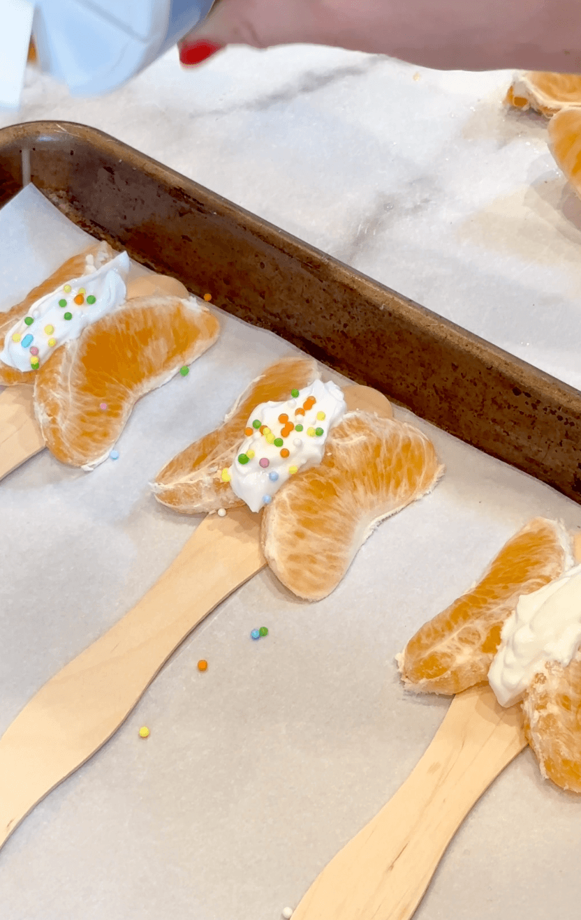 Adding sprinkles to the Greek yogurt between the mandarin slices