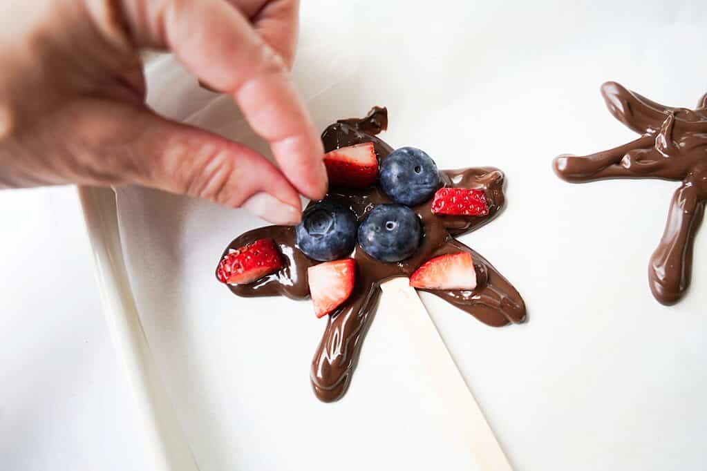 Adding strawberry pieces and blueberries to chocolate stars