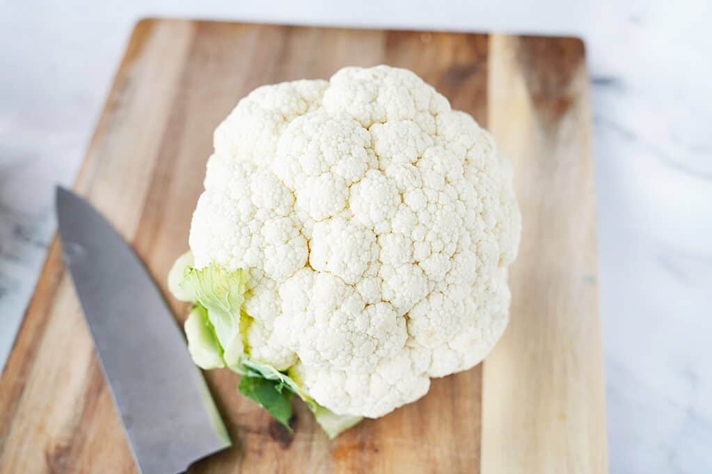 head of cauliflower on cutting board with knife