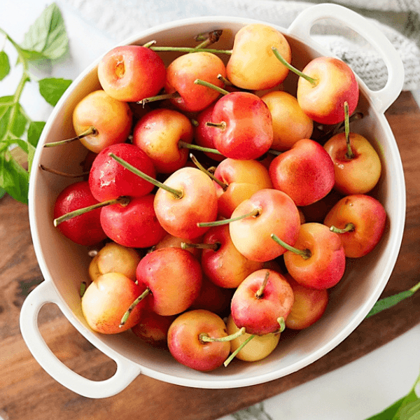 Bowl of Rainier Cherries in white bowl on cutting board