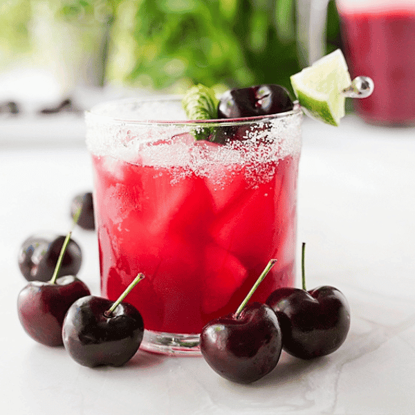Glass of Homemade Cherry Agua Fresca with Cherries around the glass