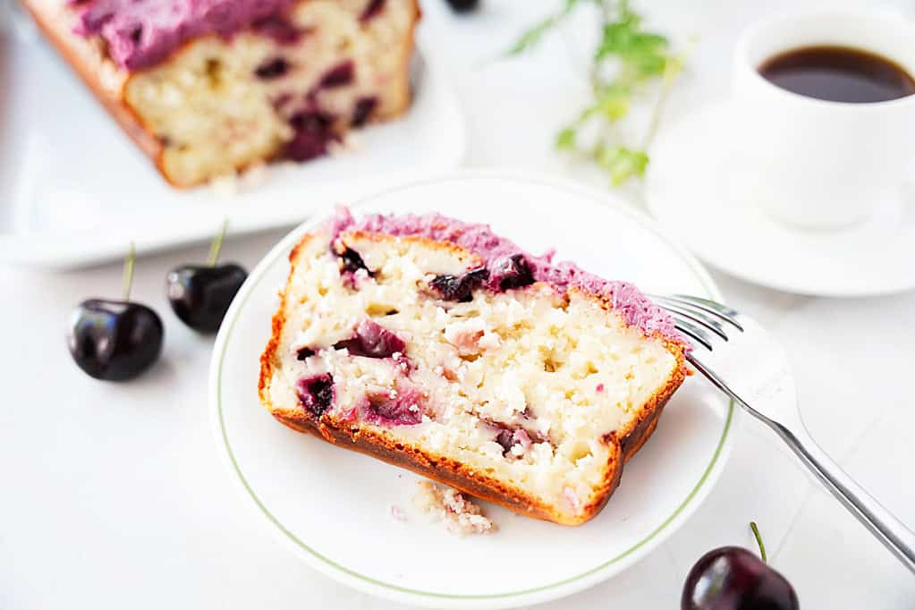 A slice of cherry bread with cherry buttercream frosting on a plate.