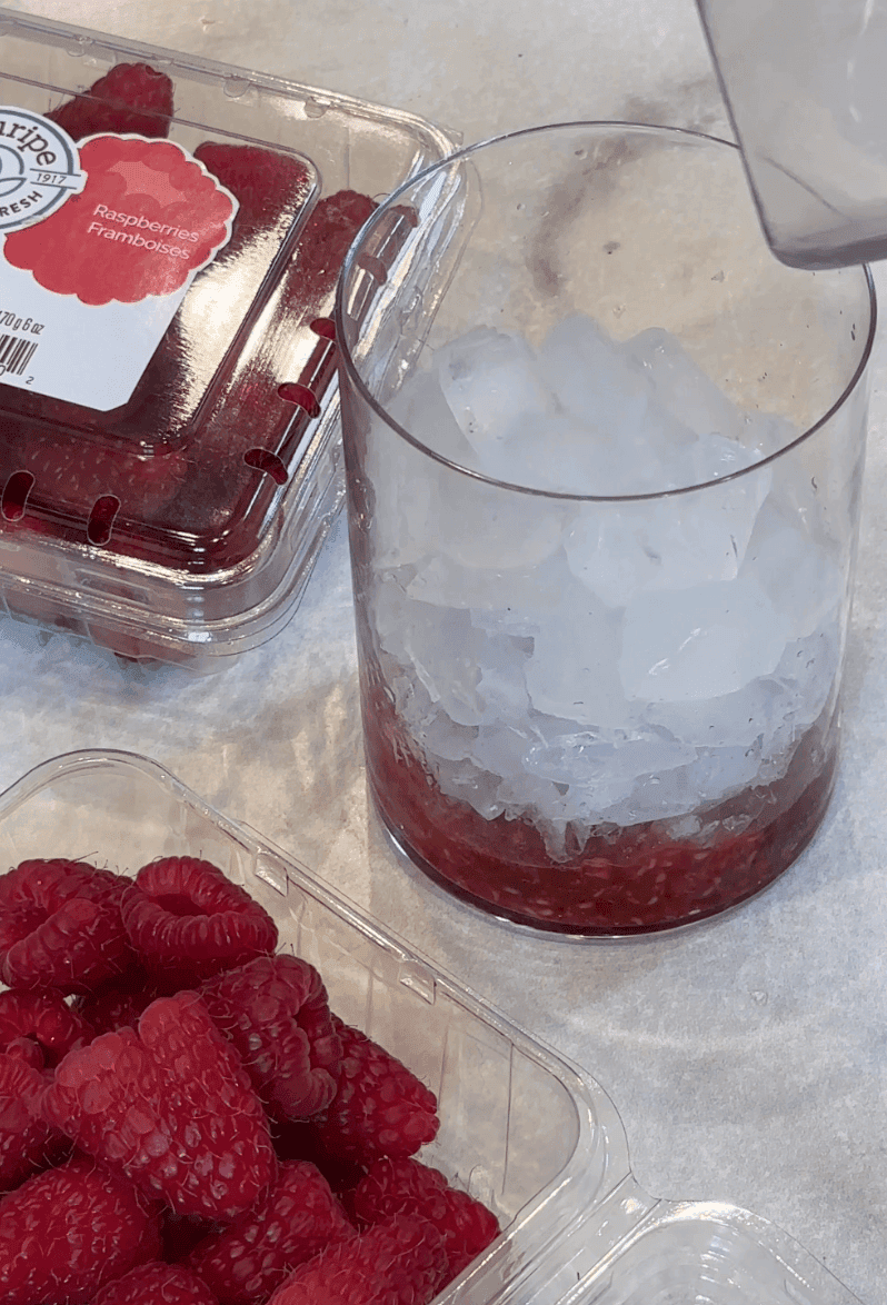 adding ice over muddled raspberries