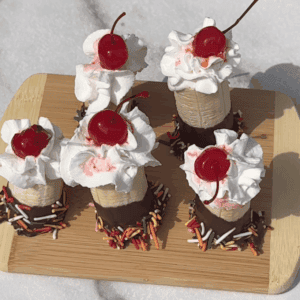 Overhead view of 5 banana split bites on a wooden board