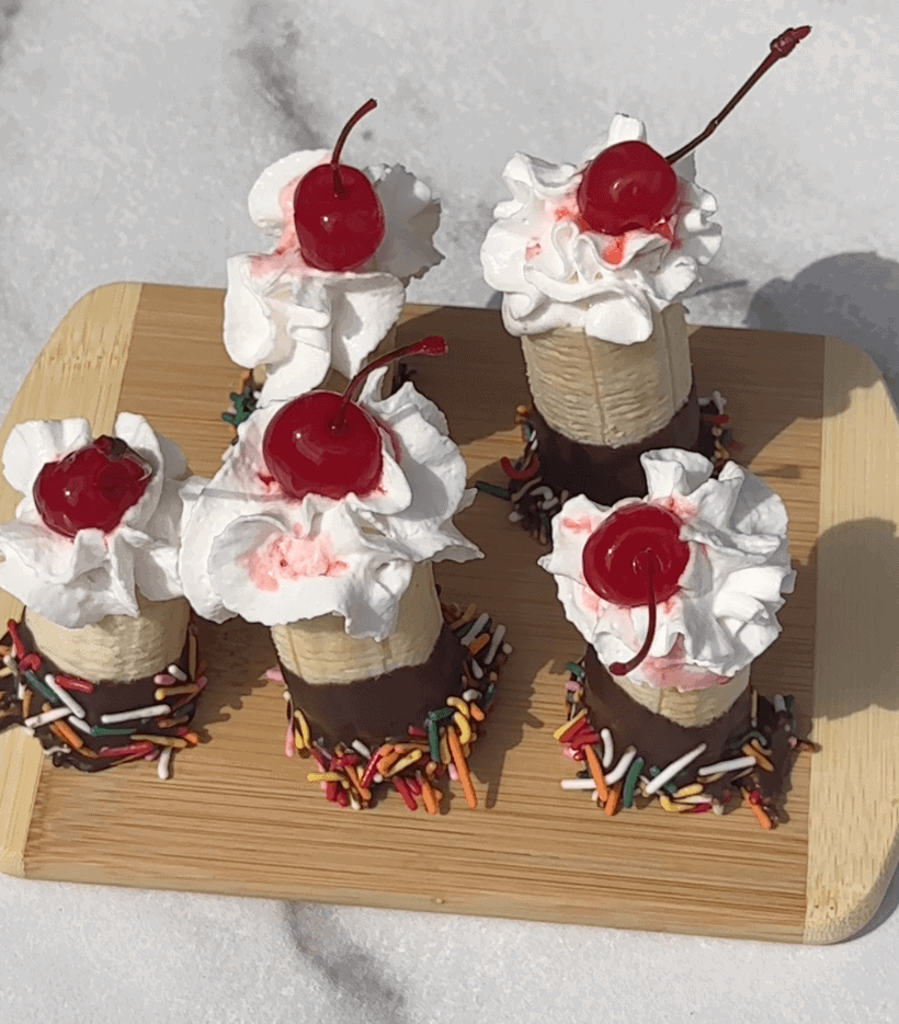 Overhead view of 5 banana split bites on a wooden board