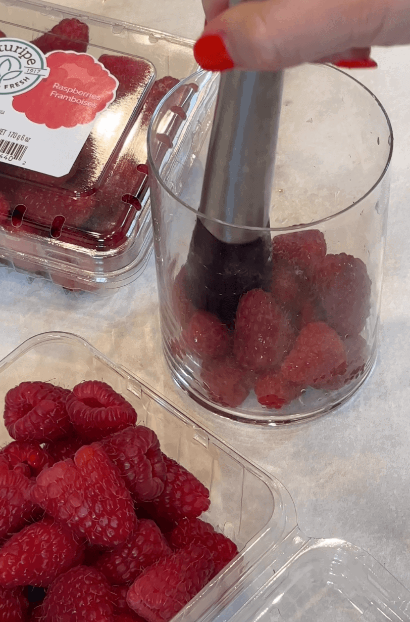 glass of raspberries getting muddled