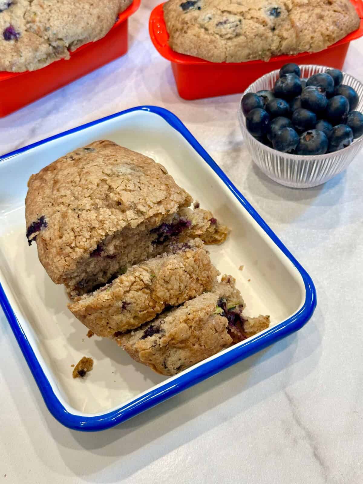 Vertical image of Blueberry Zucchini Bread in a dish cut into slices
