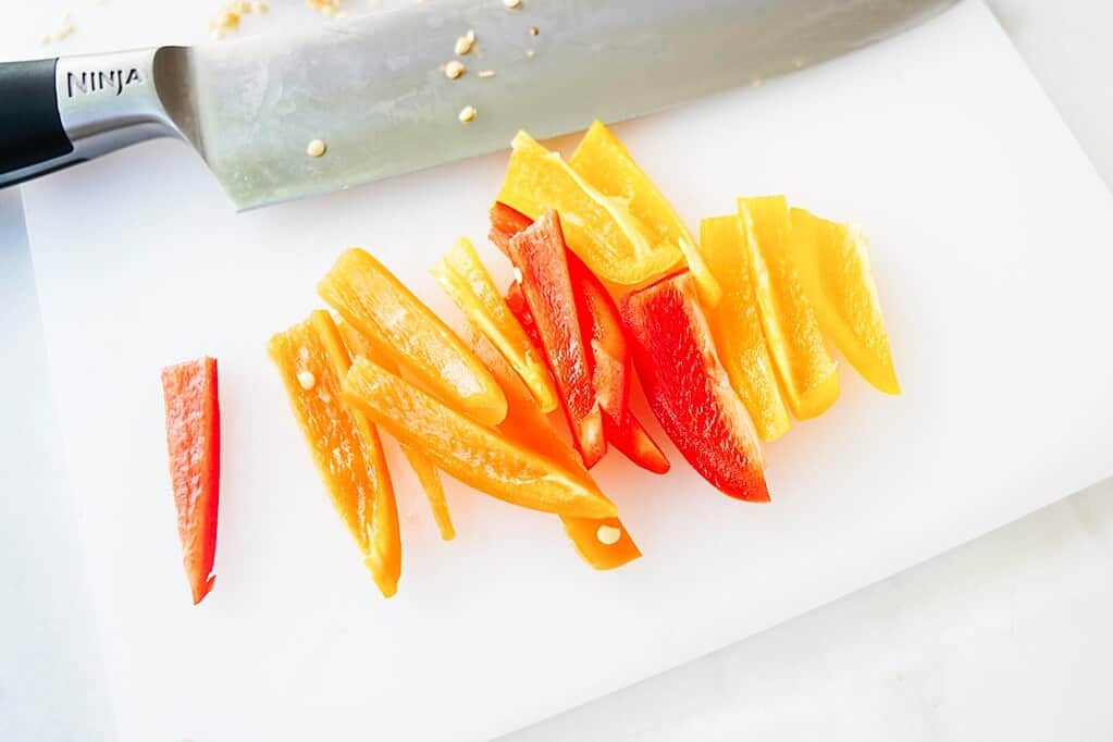 Cut mini peppers on a cutting board with a knife