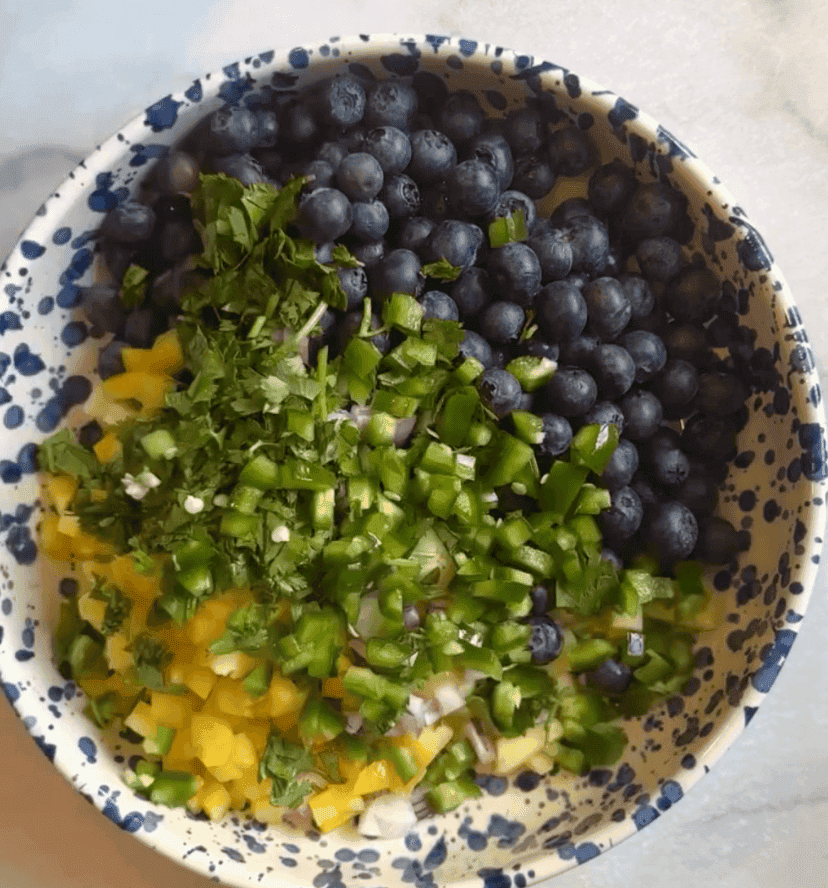 Adding all the ingredients for the blueberry pineapple fruit salsa into a bowl