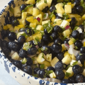 side view of blueberry pineapple salsa in a blue and white bowl