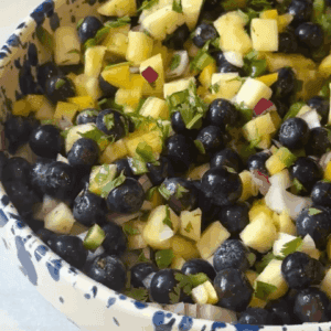 side view of blueberry pineapple salsa in a blue and white bowl